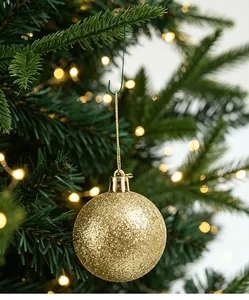 Gros plan d'un crochet de Noël vert en métal en forme de C tenant une boule dorée pailletée