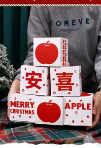 Vista dettagliata di scatole regalo di Natale bianche impilate con mela rossa e stampe