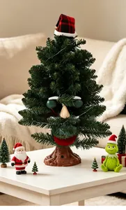 Electric musical Christmas tree with funny face and Grinch figurine details on table.