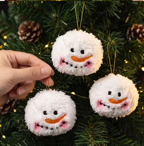 Gros plan de pompons bonhommes de neige en peluche suspendus à un sapin de Noël