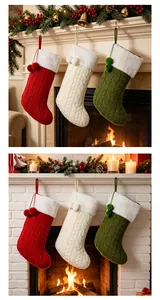 Drie gebreide kerstsokken die bij een warme open haard met decoratie hangen.
