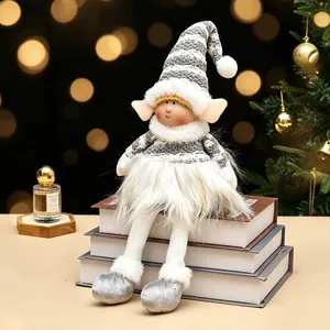 Muñeco elfo de Navidad de peluche a rayas gris y blanco sobre libros con fondo bokeh festivo