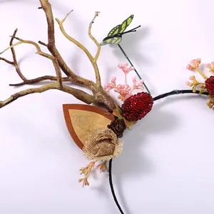 Macro view of forest-themed antler headband featuring berries, butterfly, and branch details