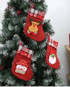Detail of small burlap Christmas stockings hanging on a tree with festive characters