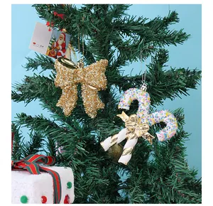 Detail van gouden glitterstrik en kralen zuurstokversiering op een groene kerstboom.