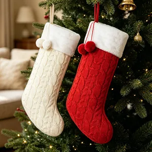 Paar gebreide kerstsokken aan de kerstboom voor een sfeervolle kerstversiering in huis.