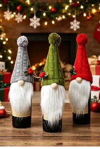 Trois couvre-bouteilles de vin nains tricotés en gris, vert et rouge sur une table.