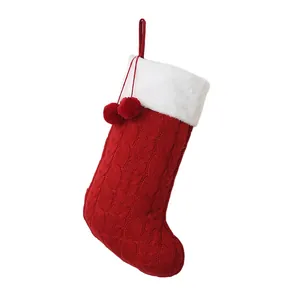 Klassieke rode gebreide kerstsok met een witte pluche rand en decoratieve rode pompons.