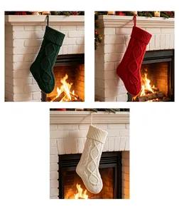 Lot de trois grandes chaussettes de Noël en tricot vert, rouge et blanc près du feu