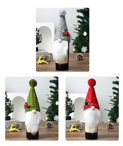 Détail de trois couvre-bouteilles de vin gnomes de Noël tricotés en rouge, vert, gris