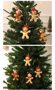 Close-up detail of golden gingerbread man ornaments hanging on a green Christmas tree