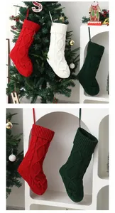 Vue détaillée de grandes chaussettes de Noël en tricot rouge, vert et blanc sur un sapin.