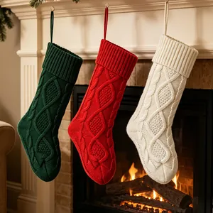 Lot de trois grandes chaussettes de Noël en tricot torsadé vert, rouge et blanc sur cheminée.