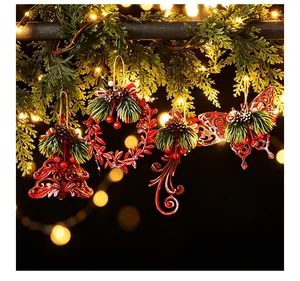 Set of red Christmas ornaments with pine needles and cones hanging on lit garland.