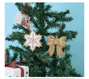 Detail van gouden glitter sneeuwvlok en strik hangend aan een groene kerstboom versiering