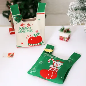 Bolsas de regalo de Navidad de punto festivo con motivos de manzana y oso en mesa blanca