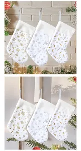 Dettaglio di calze di Natale in peluche bianco con motivi dorati di fiocchi e gnomi