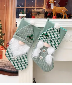Dettaglio calze natalizie in maglia verde con design di gnomo e finta pelliccia bianca