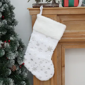 Calza di Natale in peluche bianca con motivi a fiocco di neve argentati sul camino