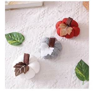Detail van drie gebreide pompoenen in rood, grijs en wit voor herfstdecoratie binnen