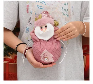Rosa Weihnachts-Kordelzug-Geschenkbeutel mit Weihnachtsmann-Motiv in Händen