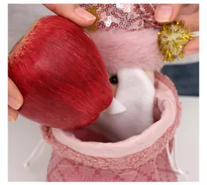 Nahaufnahme eines rosa Plüsch-Weihnachtsbeutels, der mit einem großen Apfel gefüllt wird.