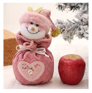 Detaillierte Makroansicht einer rosa Plüsch-Schneemann-Weihnachtstüte neben einem roten Apfel