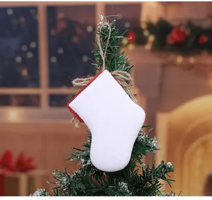 Detailansicht eines weißen Weihnachtsstrumpf-Anhängers aus Sackleinen an einem Baum.