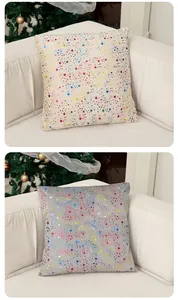 Vue détaillée de deux housses de coussin de Noël avec étoiles dorées colorées sur un canapé