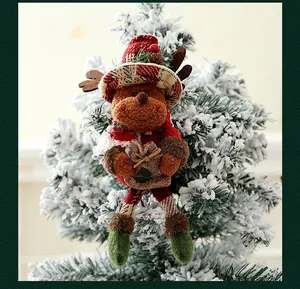 Vista detallada de un adorno de reno de peluche colgado en un árbol de Navidad nevado.