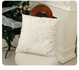 Détail d'une taie d'oreiller de Noël blanche avec motifs d'étoiles dorées.