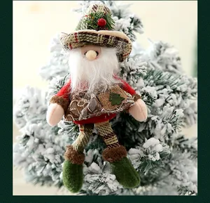Pequeño gnomo de Navidad de felpa colgado de una rama de pino nevada.