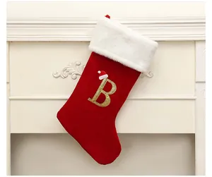 Close-up of red velvet Christmas stocking with gold glitter letter B and white fur trim
