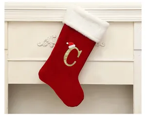 Detail view of a large red velvet Christmas stocking with a golden letter C decoration