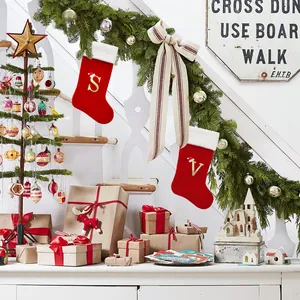 Large red Christmas stockings with gold alphabet letters S and V hanging on garland