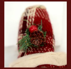 Primer plano de sombrero de muñeca navideña con piña, baya roja y agujas de pino