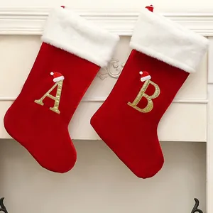 Red velvet Christmas stocking with gold glitter letters A and B and mini Santa hat details.