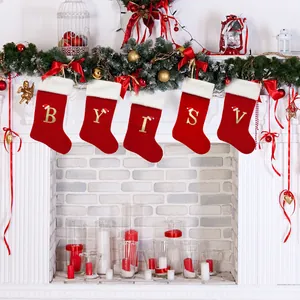 Red Christmas stockings with gold letters B, Y, I, S, V hanging on a festive fireplace mantle