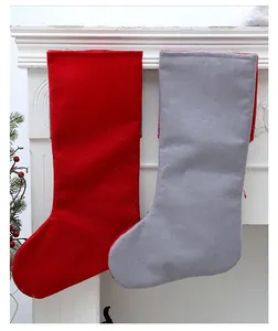 Par de calcetines de Navidad de fieltro rojo y gris colgados en una chimenea blanca