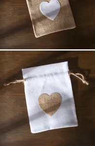 Vista dettagliata di sacchetti regalo in lino con coulisse e motivo a cuore su fondo legno
