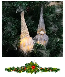 Close-up of glowing Christmas forest gnome ornaments hanging on a lush green pine tree