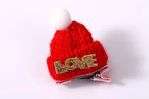 Detail der roten Mini-Strickmütze Haarspange mit weißem Bommel und glitzerndem LOVE