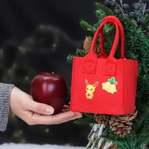 Rode vilten kerstcadeauzak met rendier- en beldecoraties voor appels of lekkernijen.