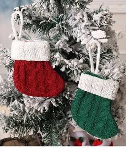 Close-up detail of mini knitted red and green Christmas socks hanging on a snowy tree