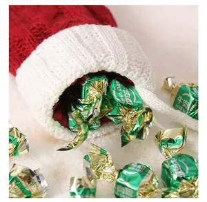 Gros plan d'une mini chaussette de Noël en tricot rouge remplie de bonbons festifs sur neige