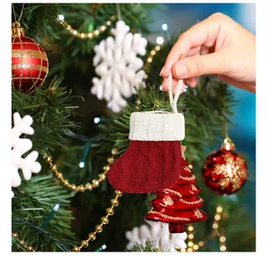 Vue détaillée d'une mini chaussette de Noël rouge tricotée accrochée au sapin de Noël