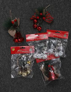 Various Christmas bell ornaments with pine needles and red bows in retail packages
