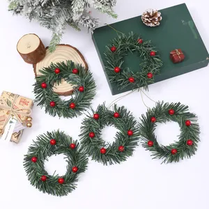 Set kleiner Weihnachtskränze aus Kiefernnadeln mit roten Beeren für Adventskerzen