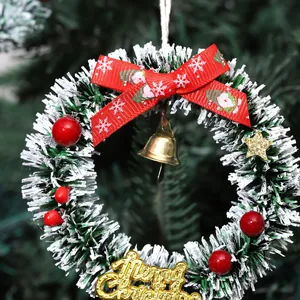Adorno navideño de corona pequeña con lazo rojo y campana dorada colgado del árbol