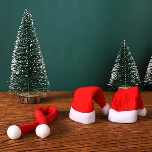 Mini red Santa hats and scarf set for Christmas wine bottle decoration on wooden table